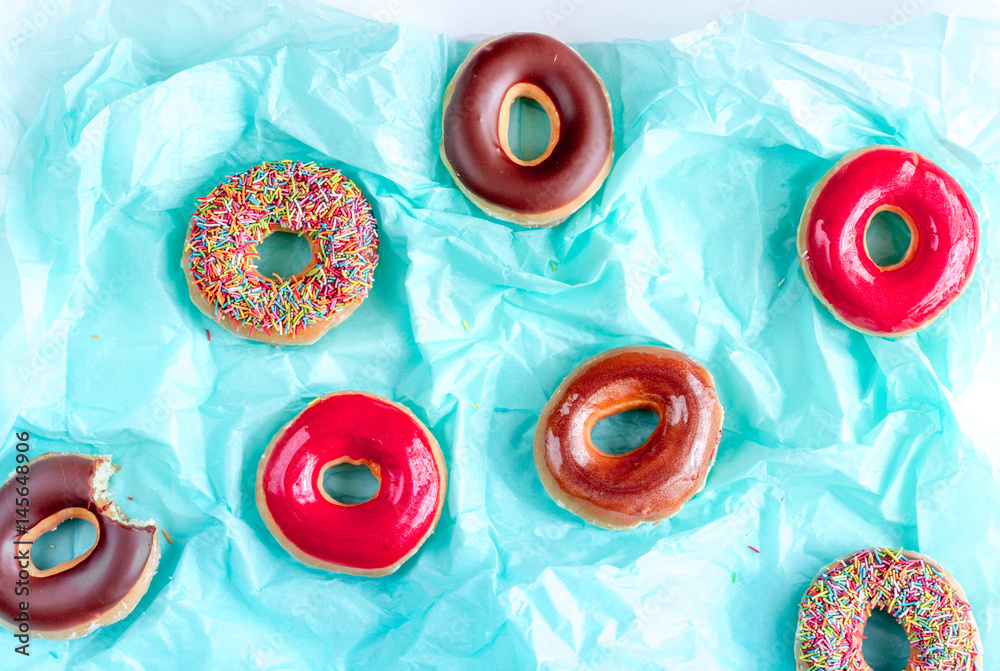 strawberry and chocolate donuts with topping blue paper background top view pattern