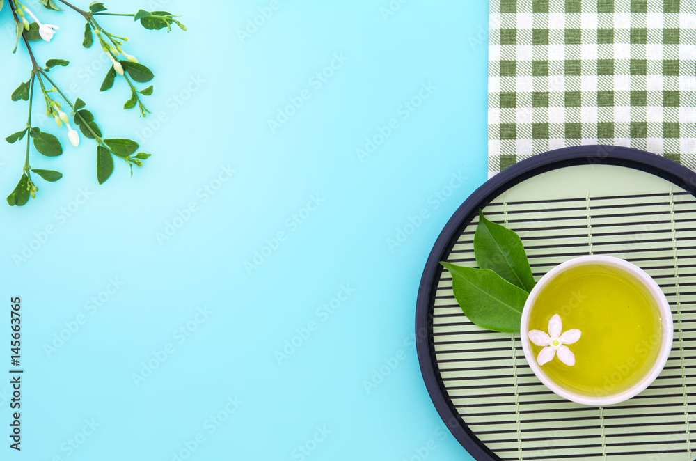 Top view shot of a hot cup of tea with green leaf decoration  with green napkin on blue background ,