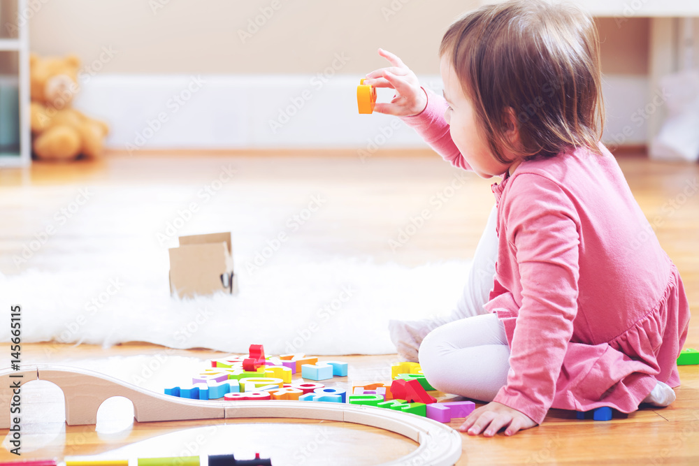 Happy toddler girl playing with toys