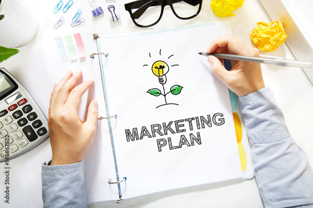 Person drawing Marketing Plan concept on white paper