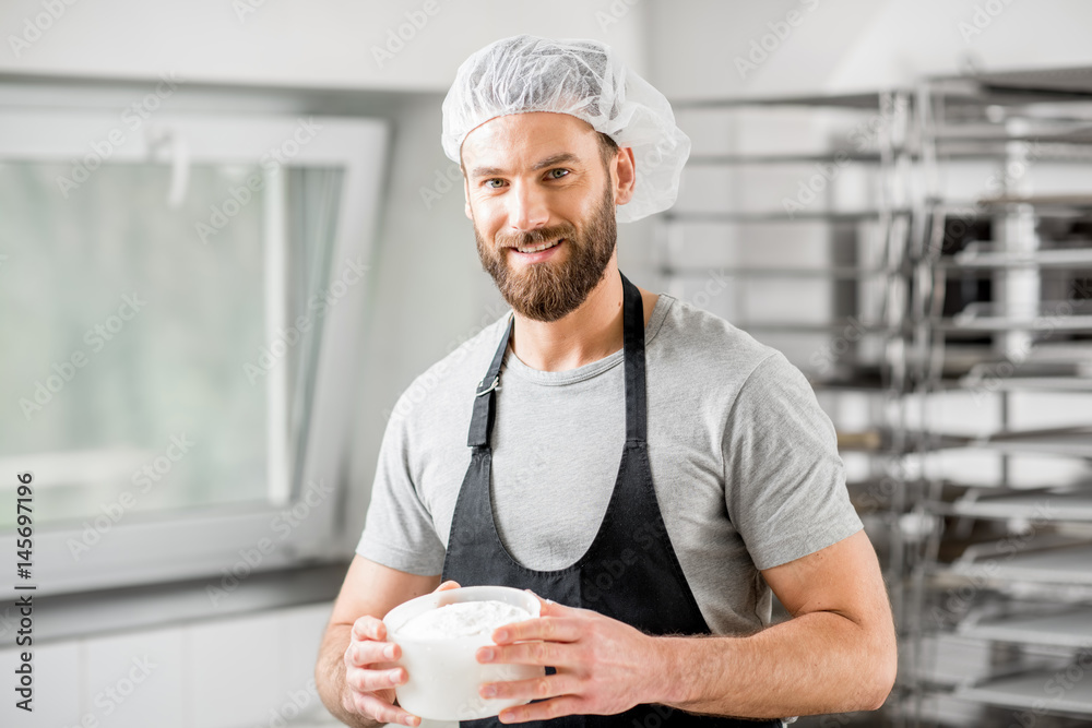 Handsome cheese maker in uniform forming cheese into molds at the small producing farm