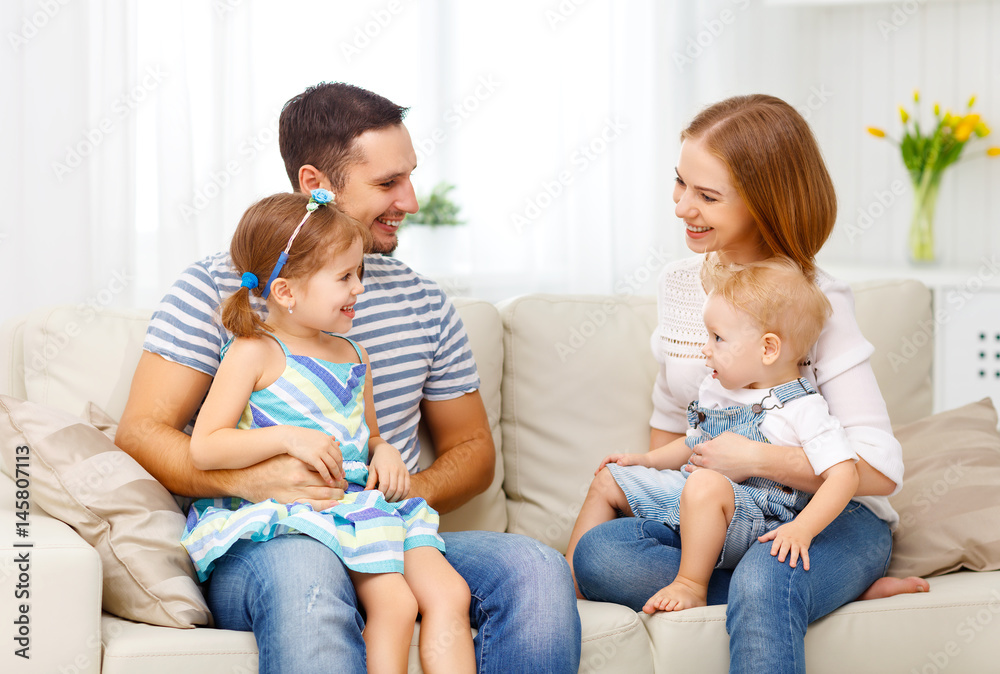 Happy family  laughing and hugging at home on sofa