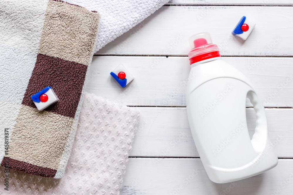 Plastic bottle with towel pile on light desk background top view