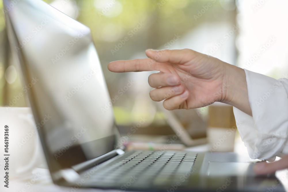 Hand pointing at computer screen in office environment