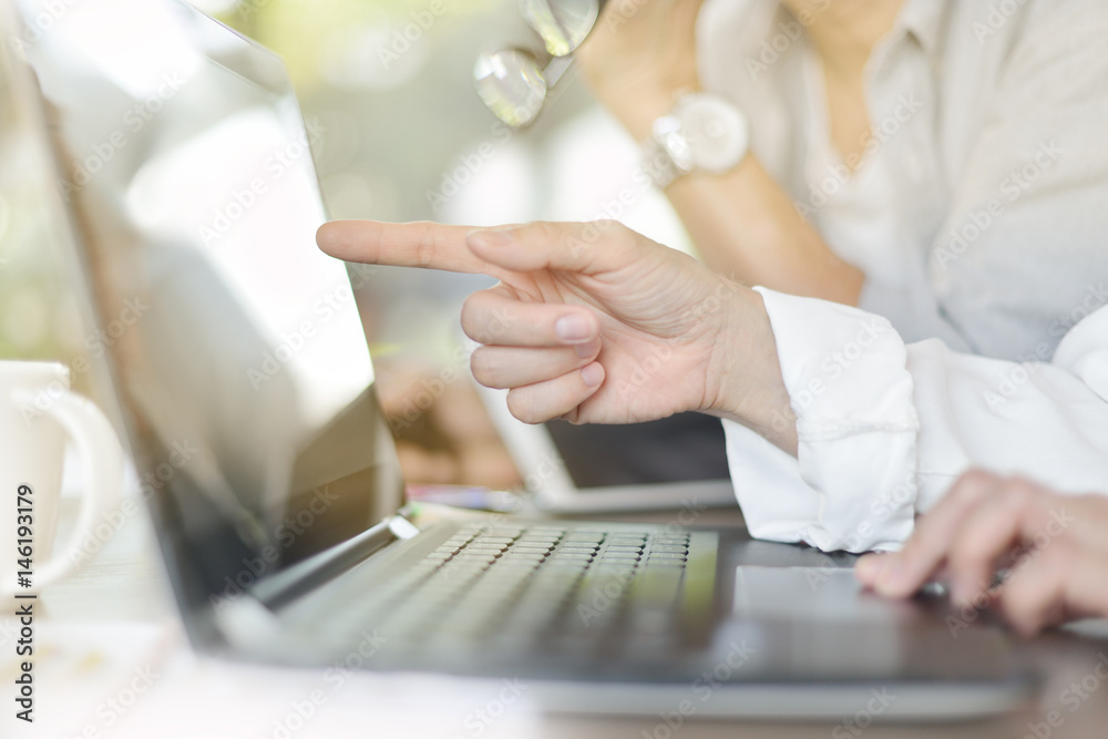 Hand pointing at computer screen in office environment