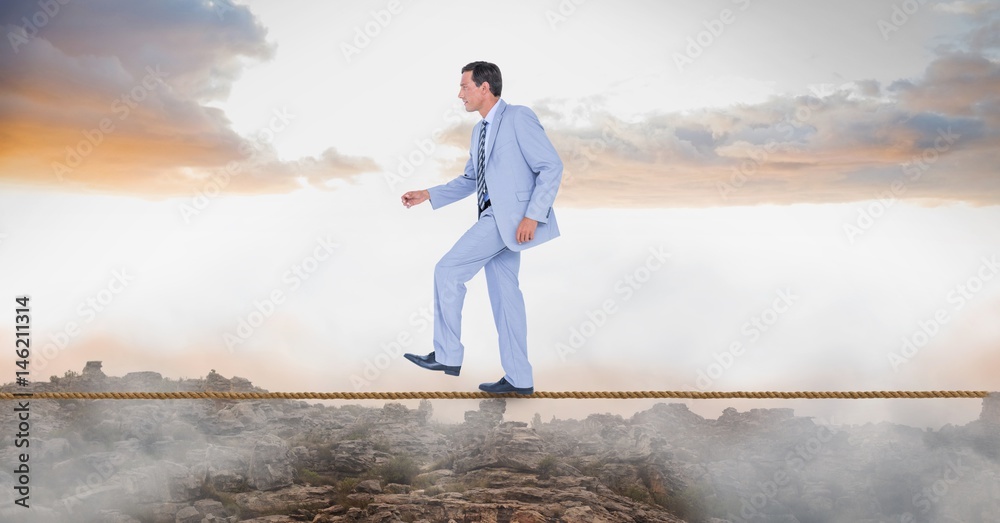 Businessman walking on rope over landscape