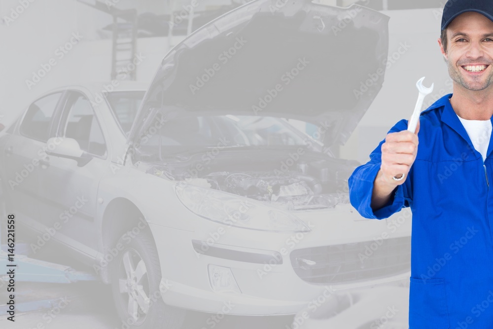 Portrait of mechanic holding wrench while standing in garage