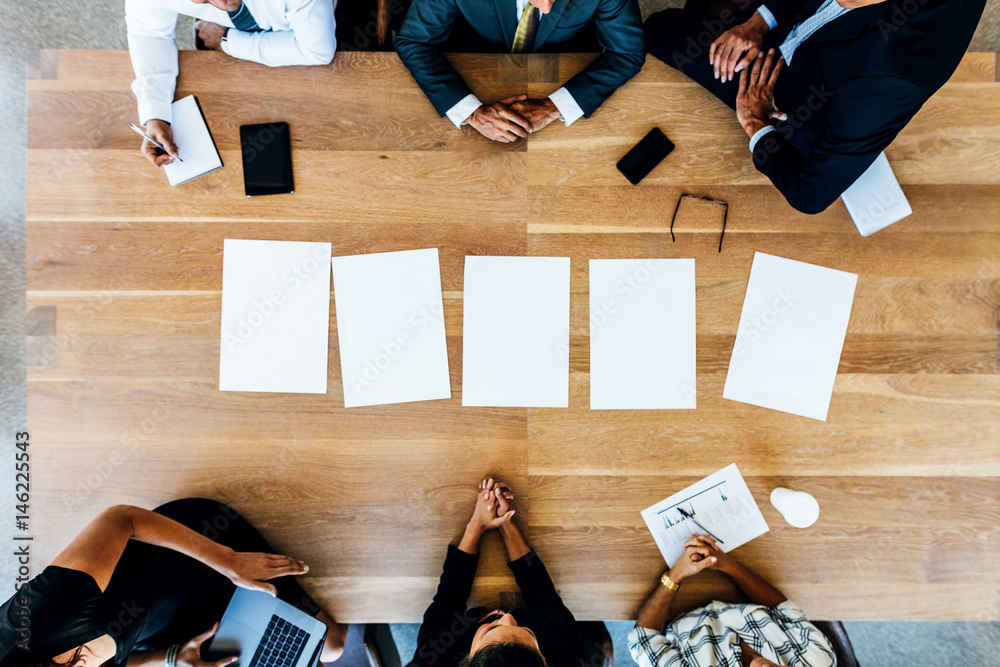 Multi-ethnic business people in meeting with blank pages on tabl