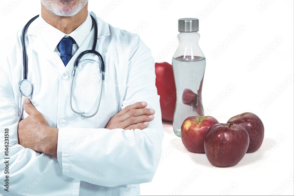 Midsection of male doctor with fruits and drink in background