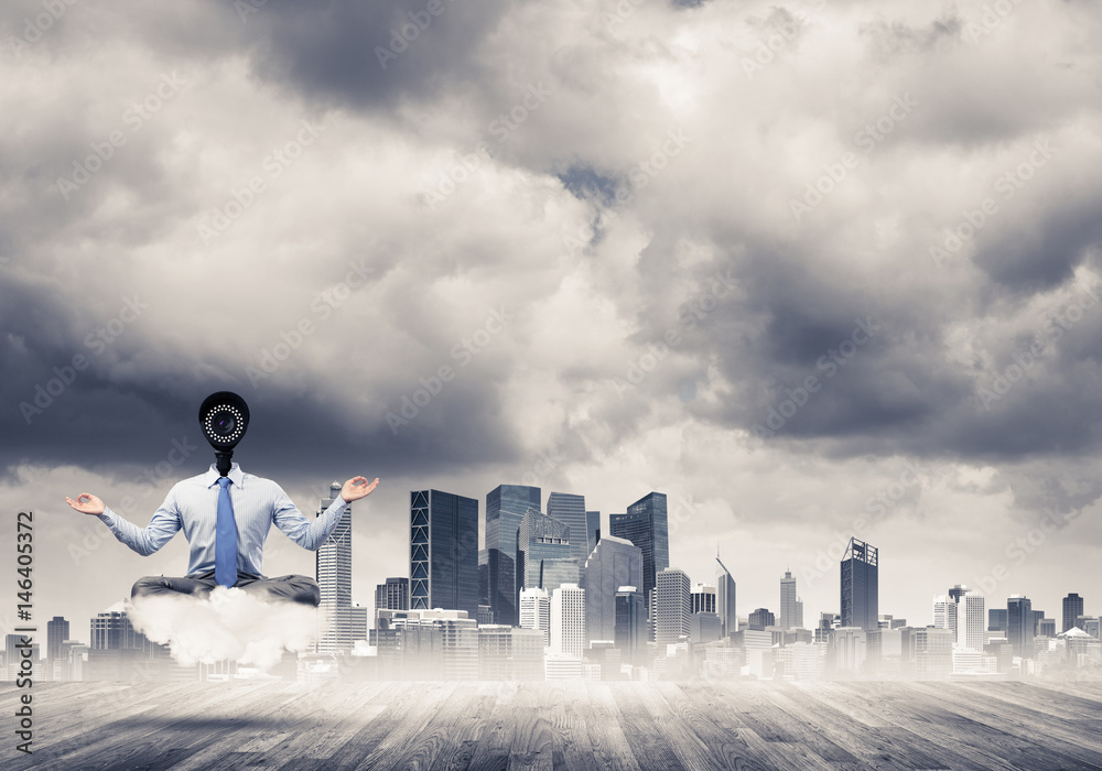 Camera headed man sitting in lotus pose on cloud against modern 