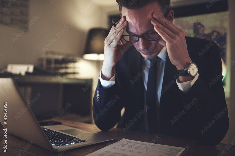 Pensive office worker accounting in the evening