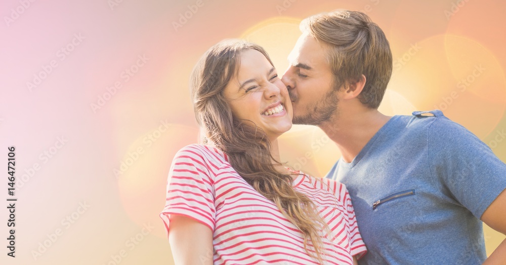 Loving man kissing happy woman on sunny day