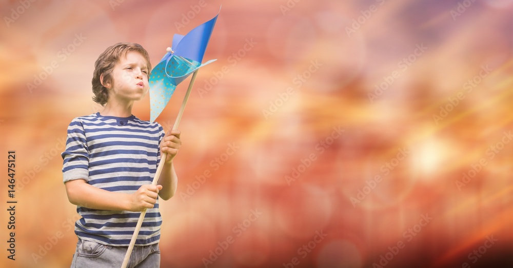 Boy blowing pinwheel over bokeh