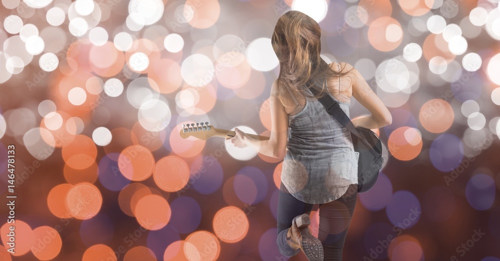 Rear view of music artist playing guitar over bokeh