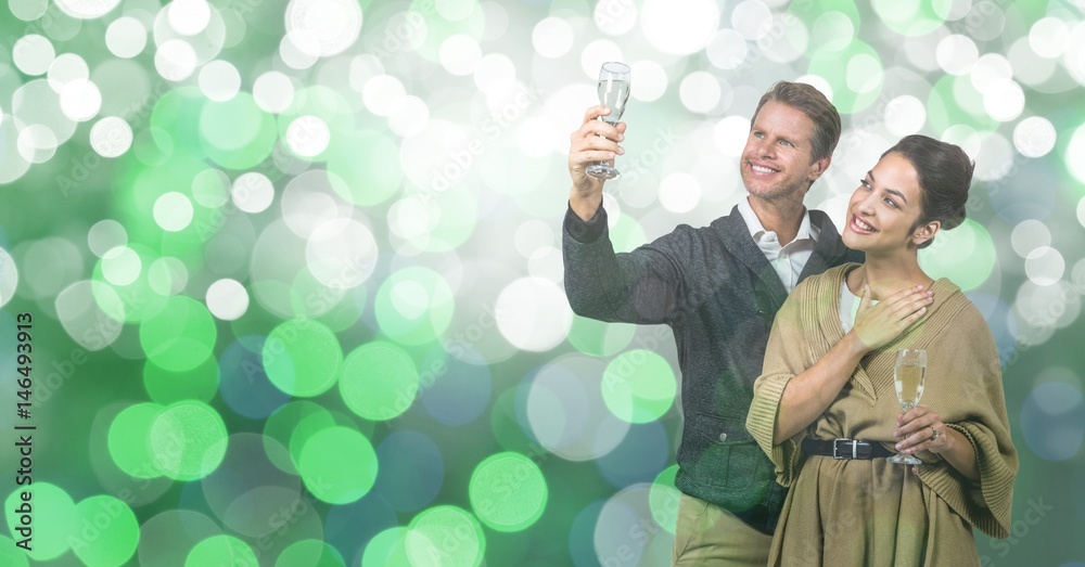 Happy couple holding champagne flutes over bokeh