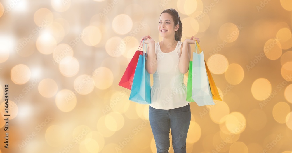 Woman smiling while holding shopping bags over bokeh