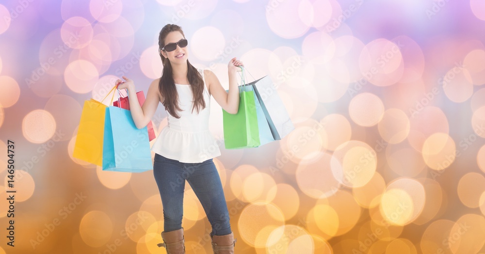 Fashionable woman carrying shopping bags over bokeh