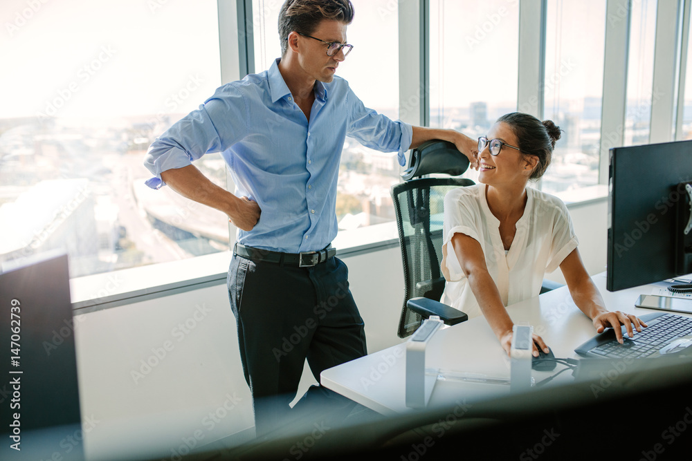 Smiling asian businesswoman with male colleague at her desk