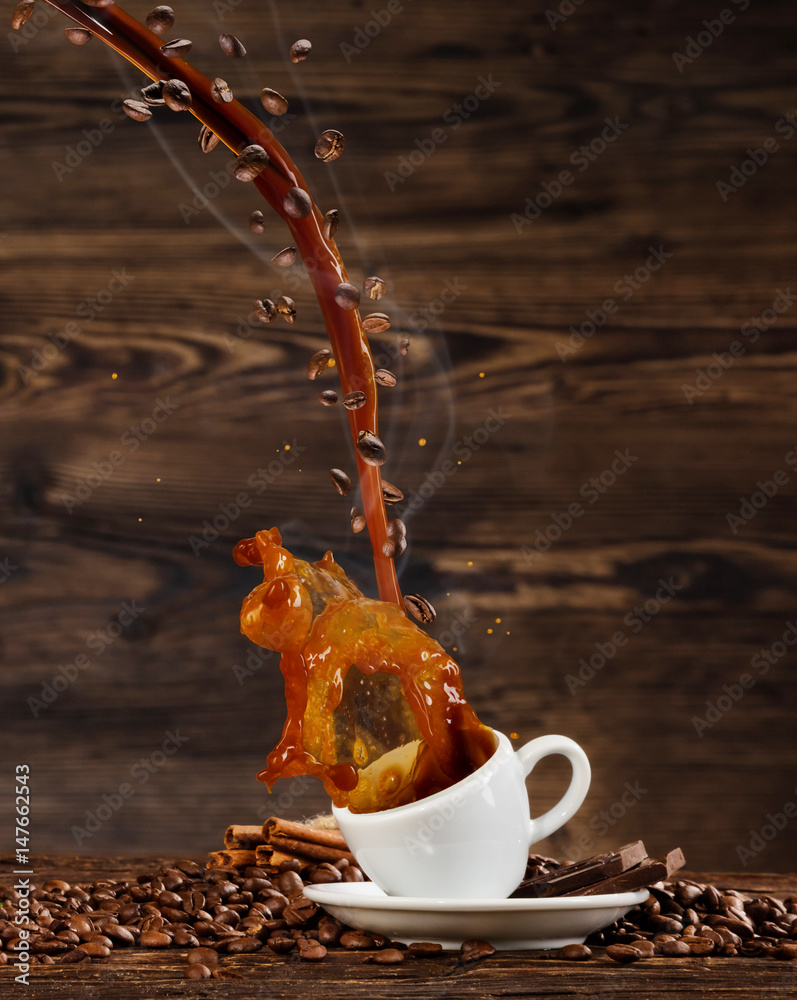 Splashing liquid of coffee into white cup on wooden table