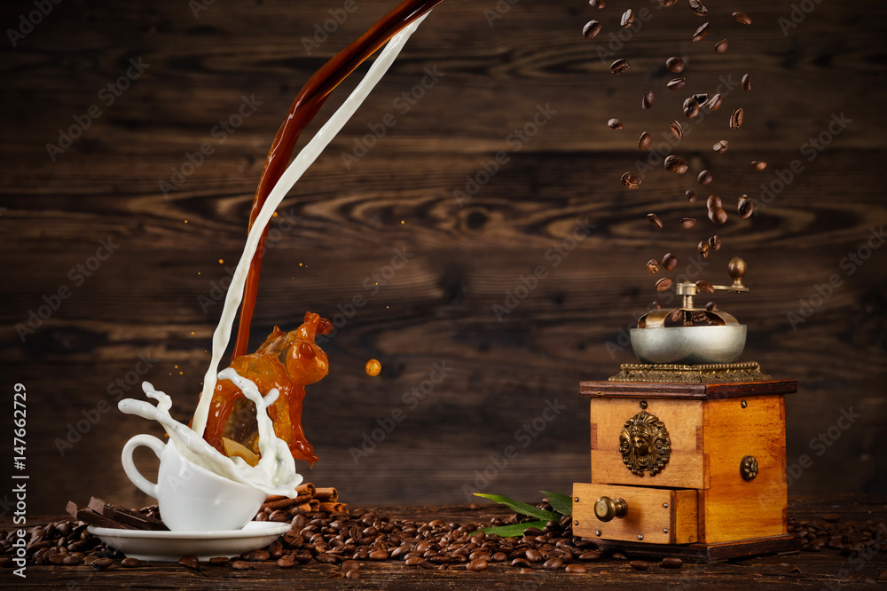 Splashing liquid of coffee and milk into white cup on wooden table