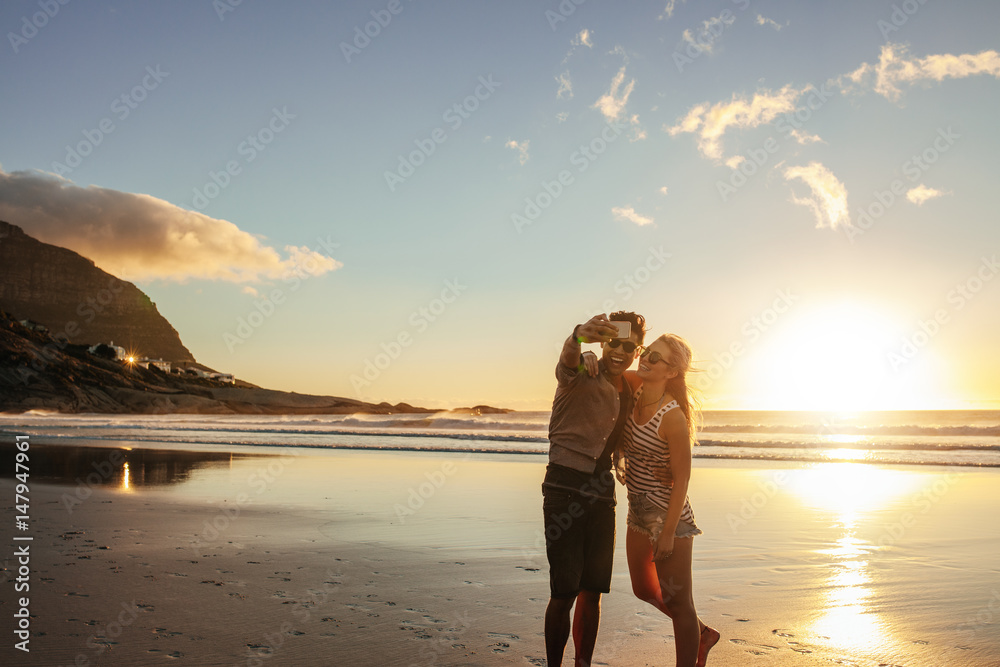 Happy young couple taking self portrait at beach