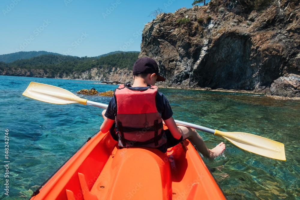 Boy in life jacket on orange kayak