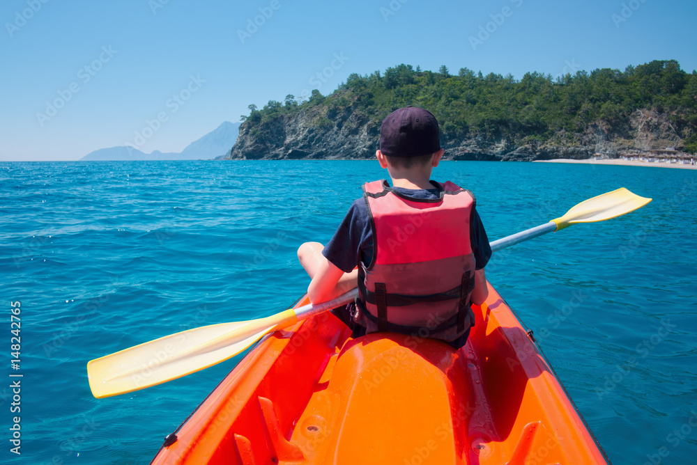 Boy in life jacket on orange kayak