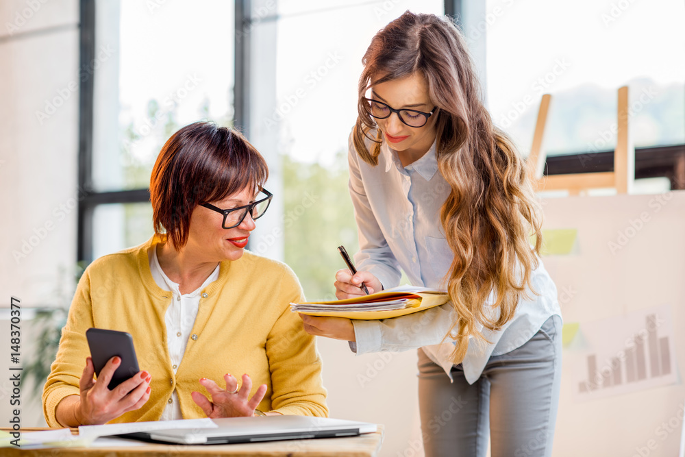 Young and older businesswomen working together on documents at the office