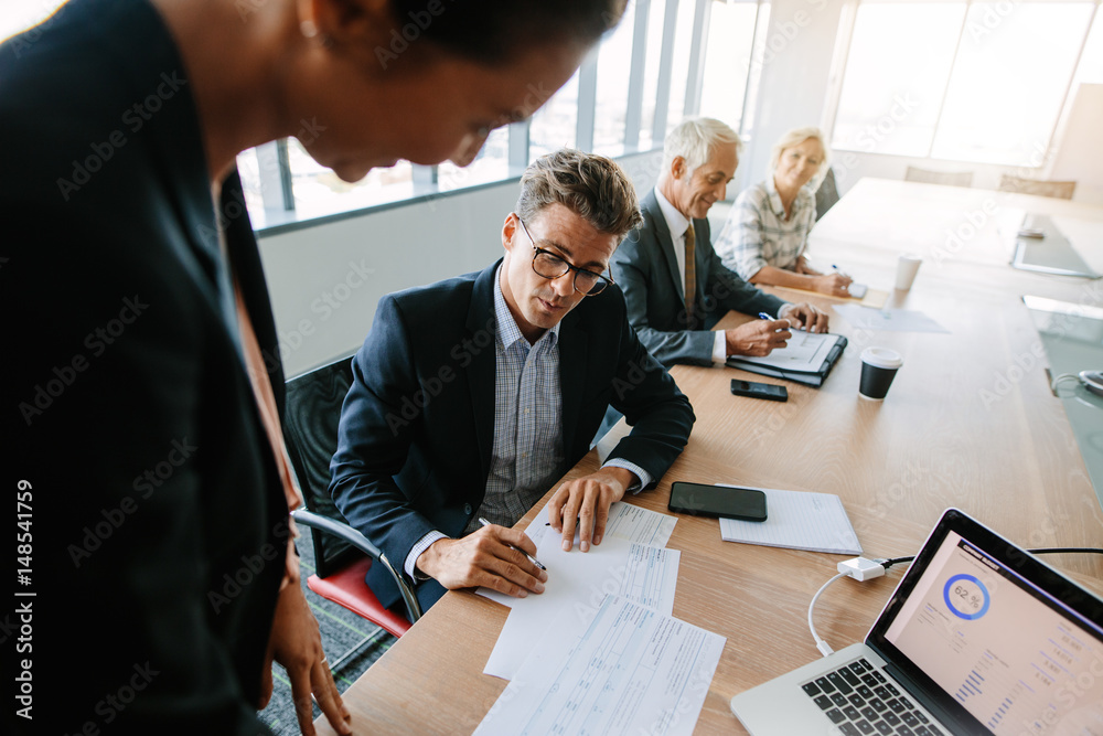 Corporate professionals discussing over documents during meeting