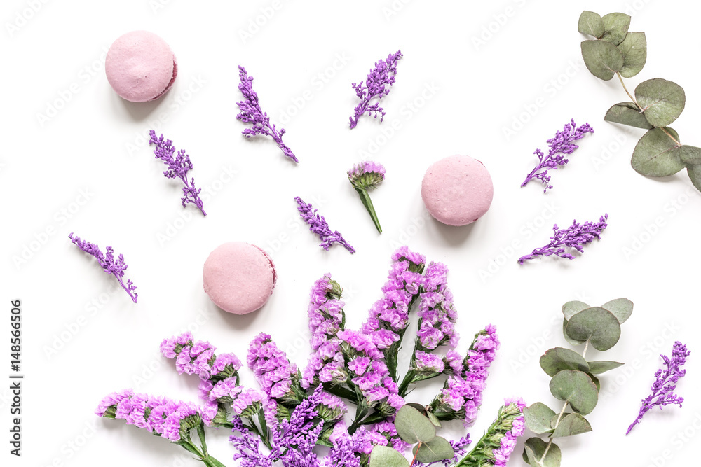 macaroons and flowers for light breakfast on white desk background top view