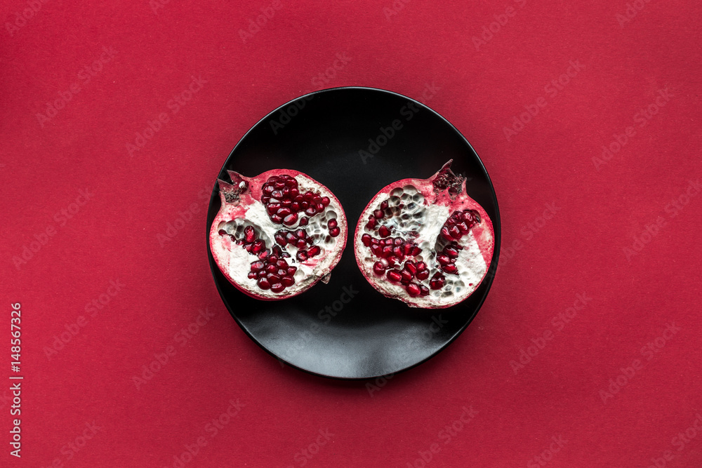 Ripe pomegranate fruit on red colored background top view space for text