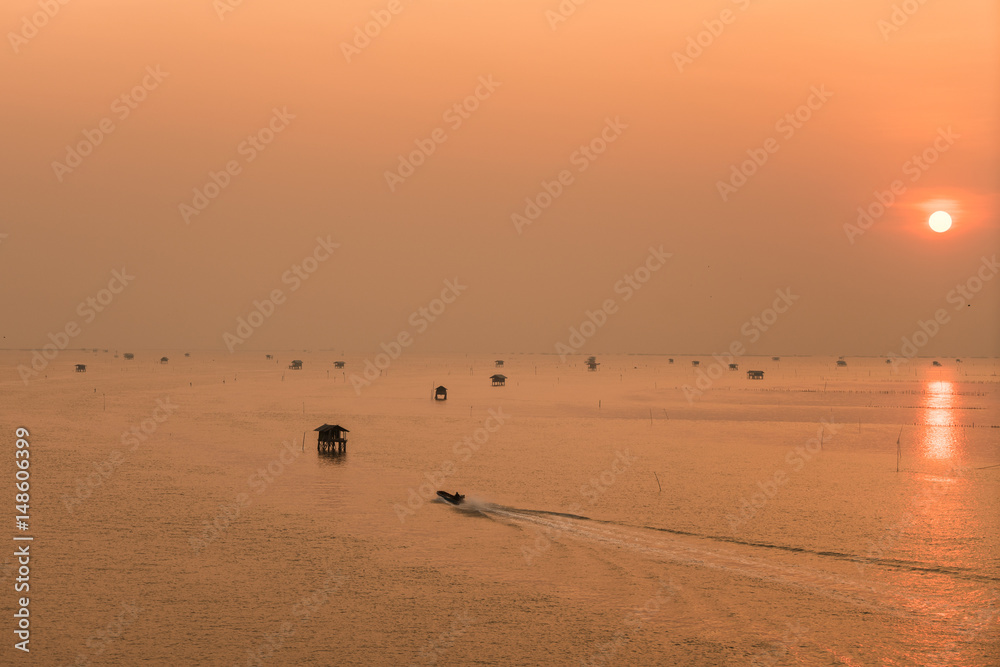 Hut and fishing boat on the sea with sunrise at Phetchaburi Province in Thailand.