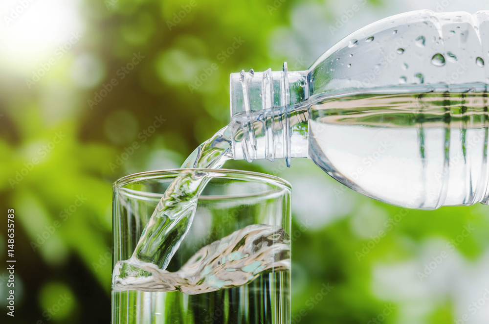 Drinking water poured into the glass and sunlight background