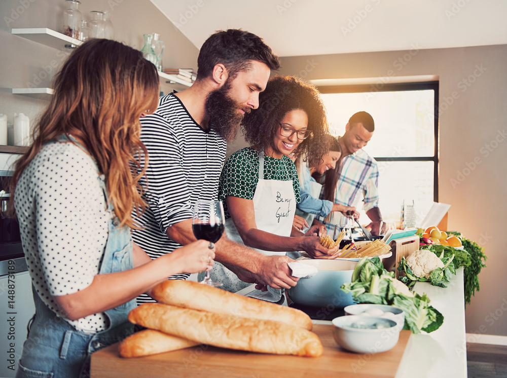 Large group of six friends cooking at table