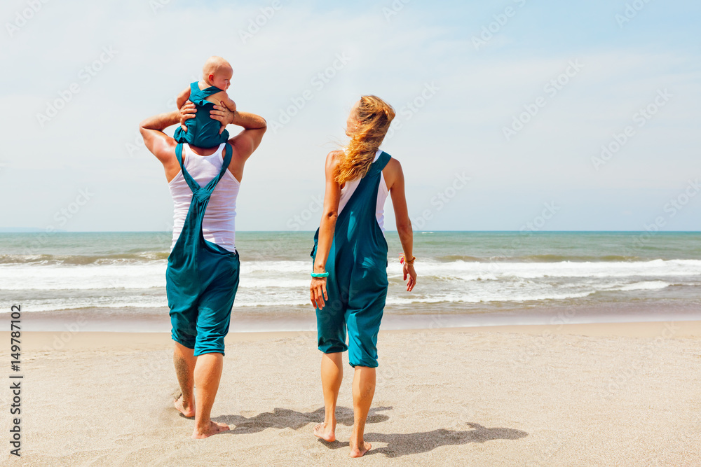 Funny portrait of happy family. People walk with fun along sea surf on sunny beach. baby son sit on 