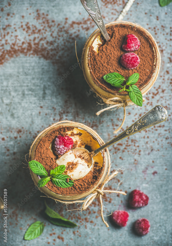 Homemade Italian dessert Tiramisu served in individual glasses with fresh mint leaves, raspberries a