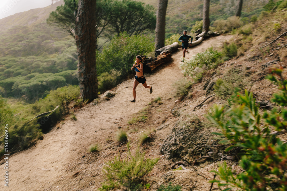 Young couple trail running on a mountain path.