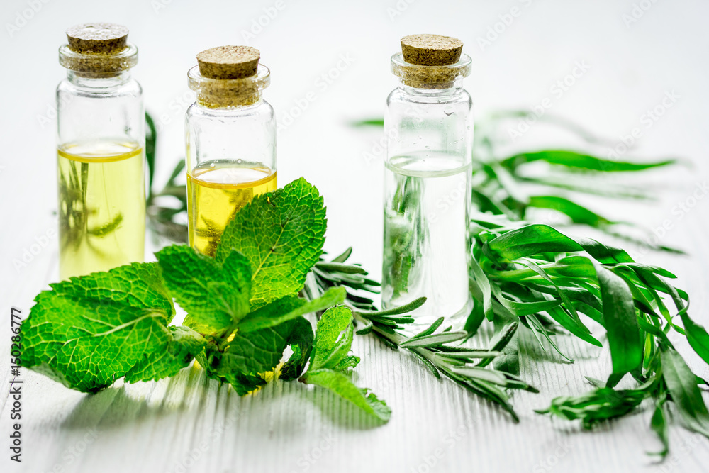 natural cosmetic oil with fresh rosemary and mint on light wooden table background