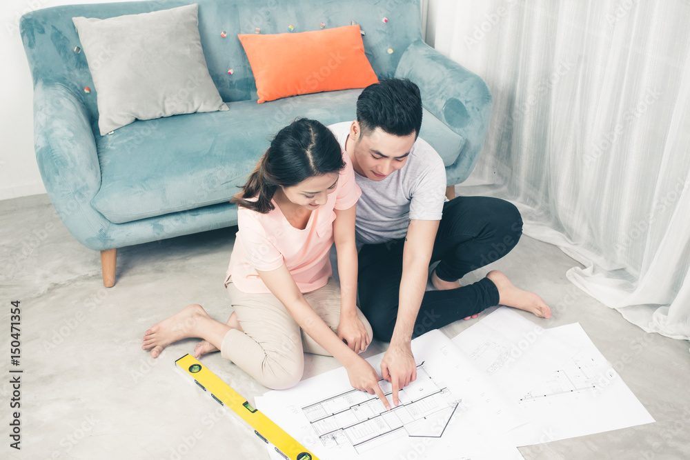 Attractive young asian adult couple looking at house plans.