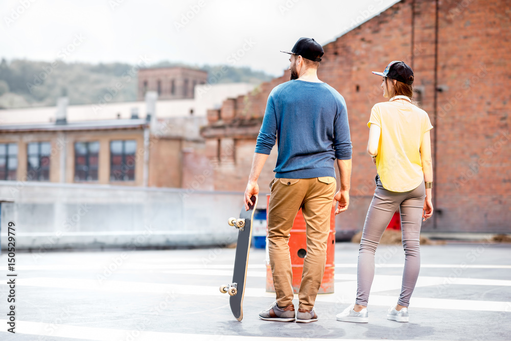 Stylish couple with skateboard outdoors