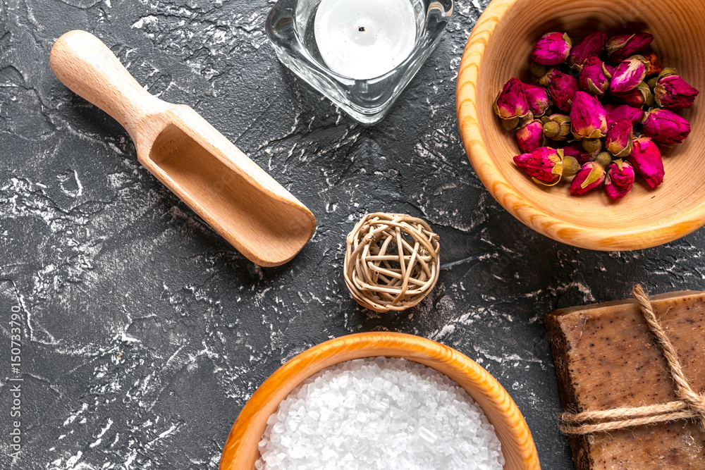 spa cosmetics with soap, salt, oil on dark background top view