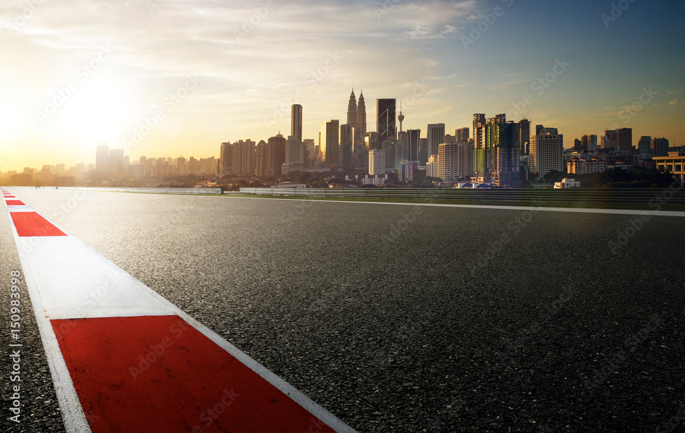 Racetrack with red and white safety sideline ,modern city background ,sunrise scene .