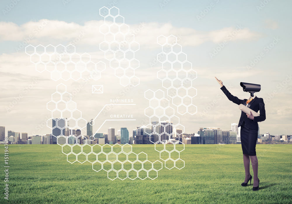 Camera headed woman standing on green grass against modern citys