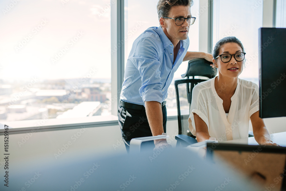 Corporate professionals looking at computer monitor in office