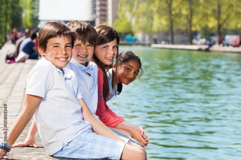 Happy friends sitting on the river embankment