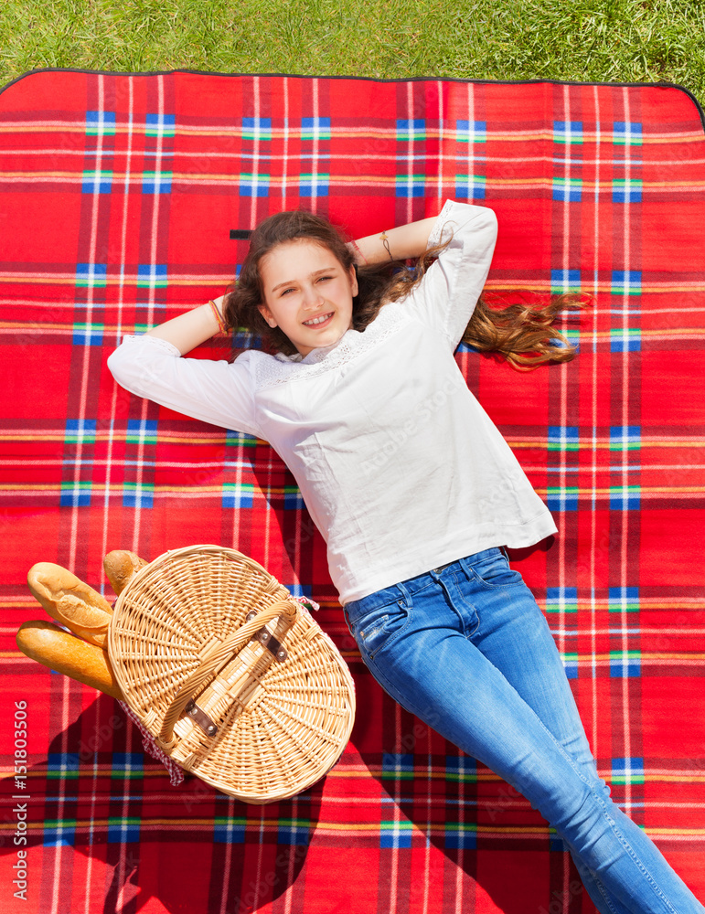 Girl laying on checkered plaid next to hand basket