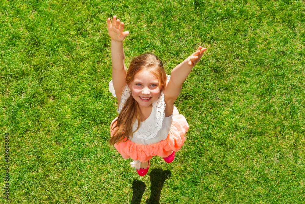 Happy girl having fun jumping on the green grass