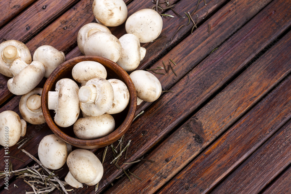 Mushrooms champignon on wooden background. Copy space.