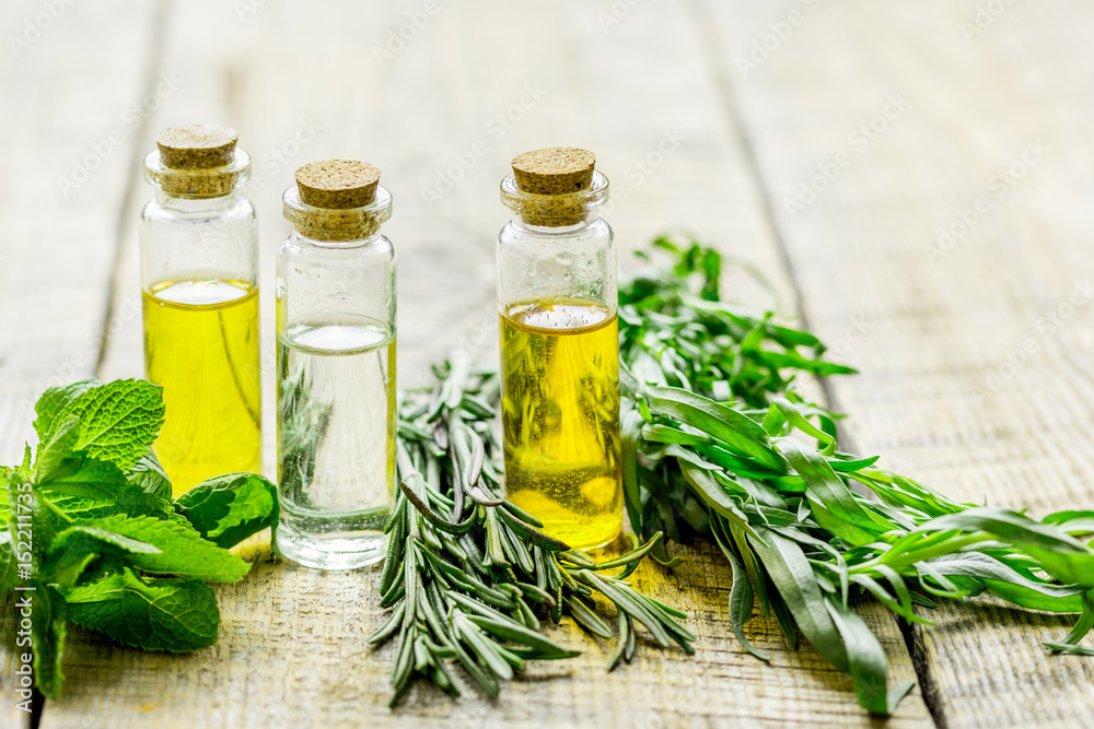 organic oil in bottle with rosemary and mint on light table background