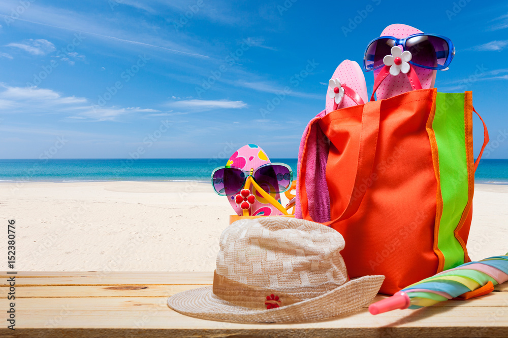 Beach accessory,hat,sunglasses,shoes,umbrella on wooden with tropical beach background, concept summ